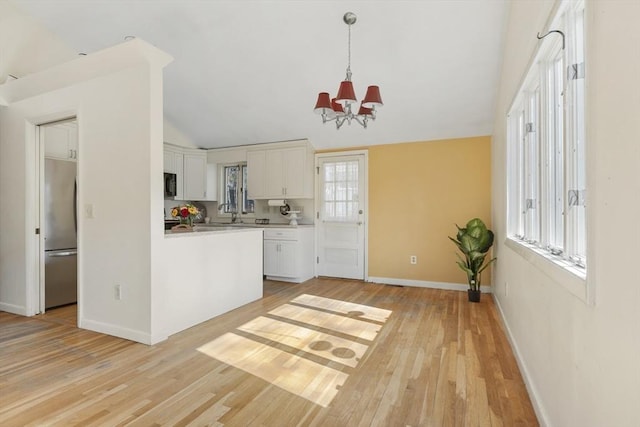 kitchen featuring white cabinetry, freestanding refrigerator, light wood finished floors, a chandelier, and light countertops