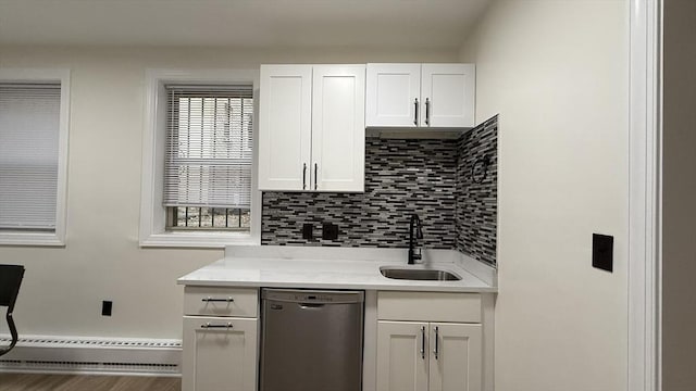 kitchen with tasteful backsplash, a baseboard heating unit, light countertops, stainless steel dishwasher, and a sink