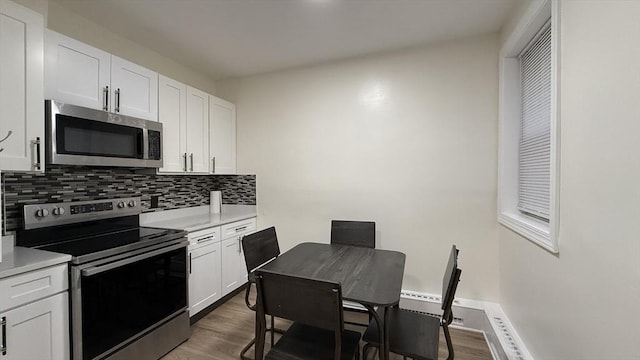 kitchen featuring decorative backsplash, appliances with stainless steel finishes, wood finished floors, and light countertops