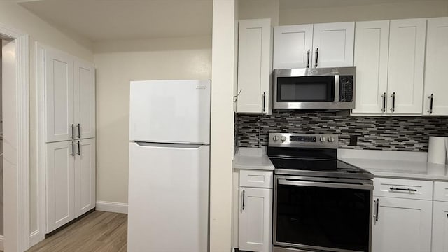 kitchen with tasteful backsplash, white cabinetry, stainless steel appliances, and light countertops