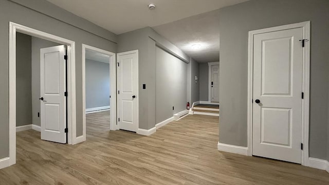 hall featuring baseboards and light wood-style floors