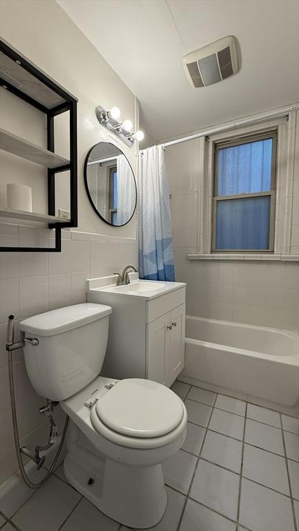 bathroom with tile patterned flooring, visible vents, toilet, and tile walls