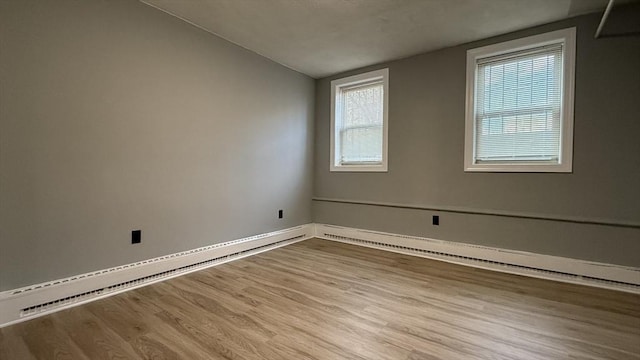 spare room with vaulted ceiling, a baseboard heating unit, and wood finished floors