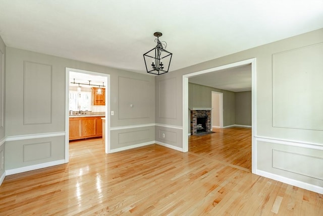 759 Williams St, Longmeadow, MA 01106 - unfurnished dining area with a decorative wall, a chandelier, light wood-style flooring, and a fireplace