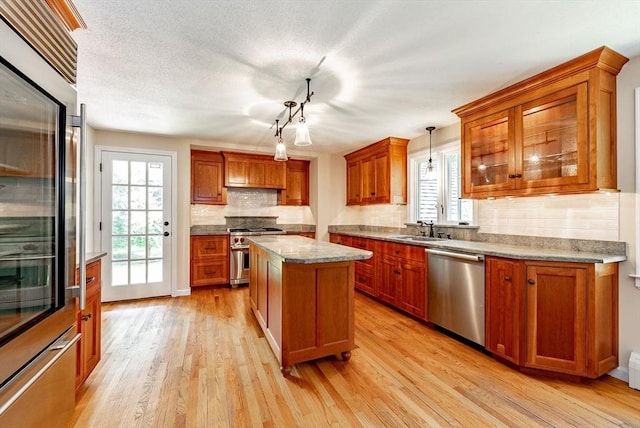 759 Williams St, Longmeadow, MA 01106 - kitchen with high end appliances, light wood finished floors, tasteful backsplash, brown cabinetry, and hanging light fixtures