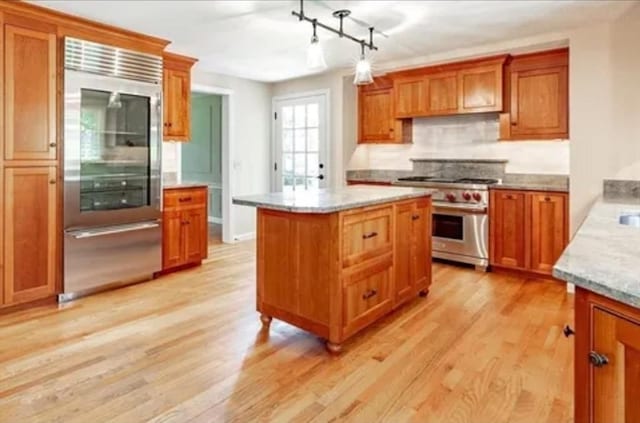 759 Williams St, Longmeadow, MA 01106 - kitchen featuring high end appliances, light wood-style floors, brown cabinetry, and tasteful backsplash