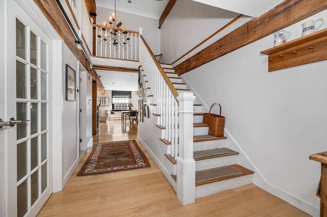 stairs featuring an inviting chandelier and wood-type flooring