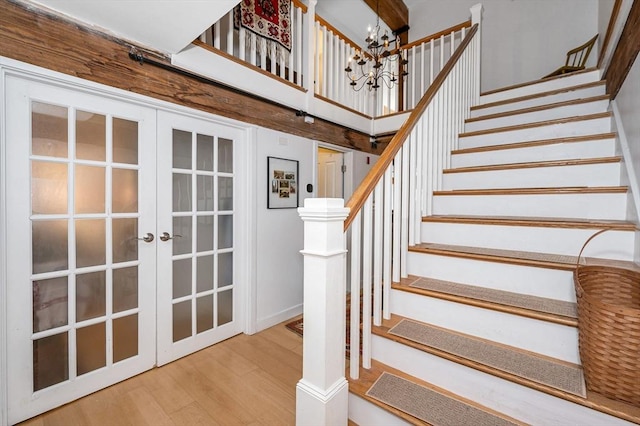 stairs featuring french doors, wood-type flooring, and a notable chandelier