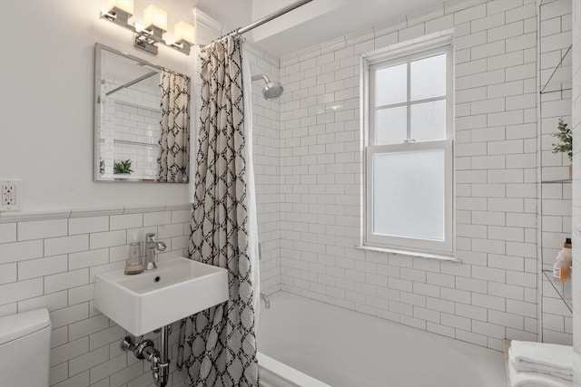 full bathroom with shower / tub combo, a sink, tile walls, and toilet