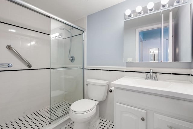 bathroom with tile walls, walk in shower, vanity, and toilet