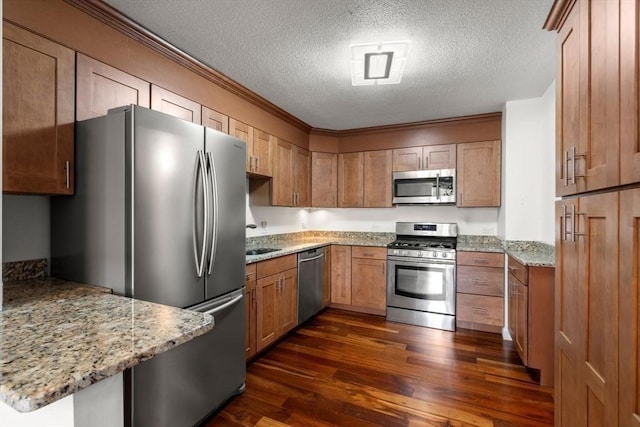 kitchen with kitchen peninsula, a textured ceiling, light stone counters, and appliances with stainless steel finishes