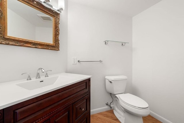 bathroom with toilet, vanity, and hardwood / wood-style floors