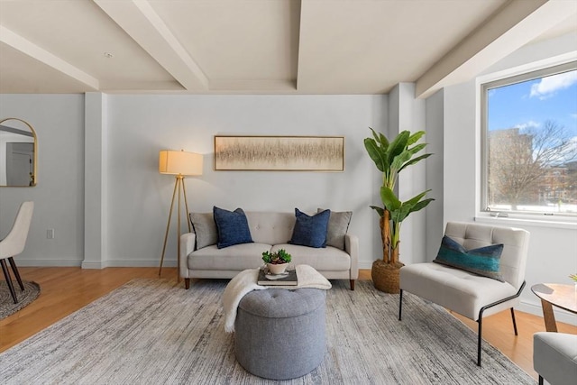 living area with beam ceiling, baseboards, and wood finished floors