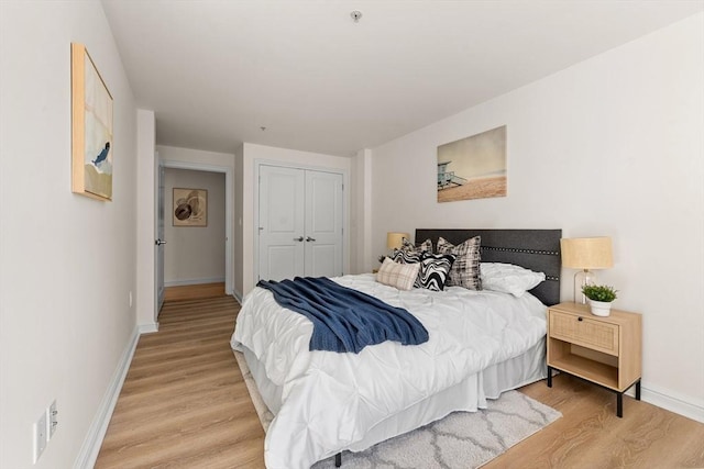 bedroom with light wood finished floors, baseboards, and a closet