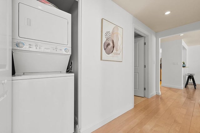 washroom with recessed lighting, light wood-style flooring, stacked washing maching and dryer, laundry area, and baseboards