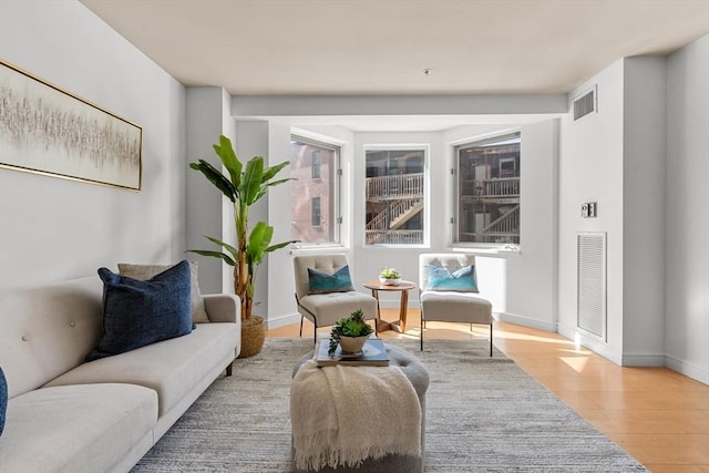 living area featuring wood finished floors, visible vents, and baseboards