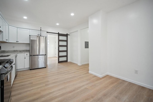 kitchen with sink, light hardwood / wood-style flooring, white cabinetry, stainless steel appliances, and a barn door