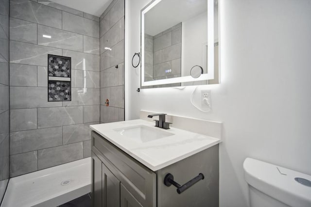 bathroom with vanity, tiled shower, and toilet