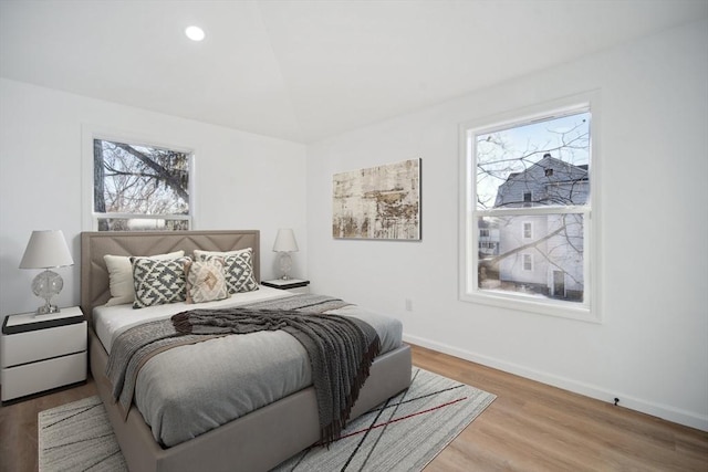 bedroom featuring multiple windows, lofted ceiling, and light hardwood / wood-style floors