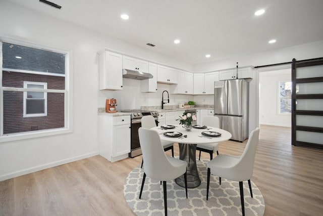 dining area featuring sink, light hardwood / wood-style flooring, and a barn door