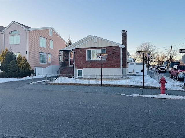 view of front facade featuring brick siding, a fenced front yard, and a chimney