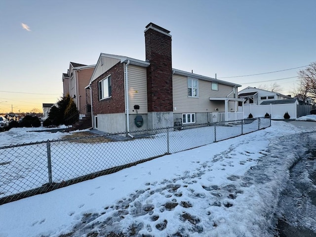 view of snow covered exterior with fence and a chimney