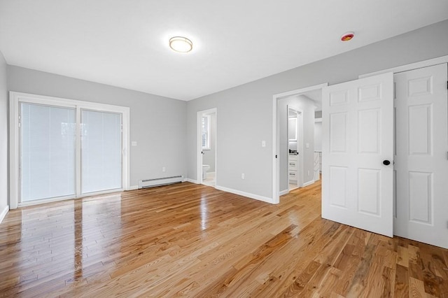 unfurnished bedroom featuring light wood-style flooring, a baseboard heating unit, and baseboards
