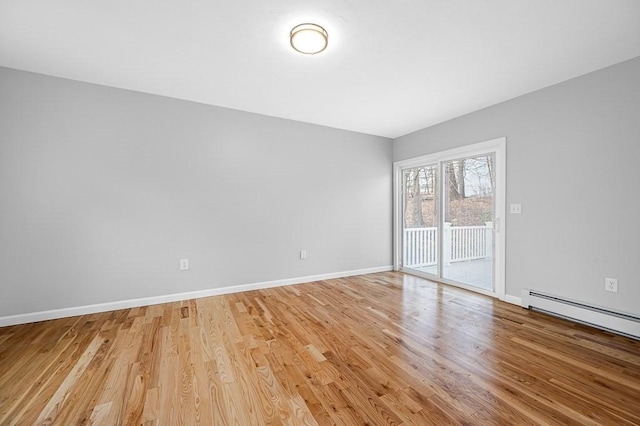 empty room with light wood-style flooring, a baseboard heating unit, and baseboards