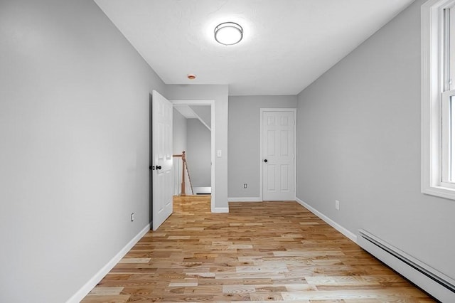 unfurnished bedroom featuring baseboards, light wood-type flooring, and a baseboard heating unit