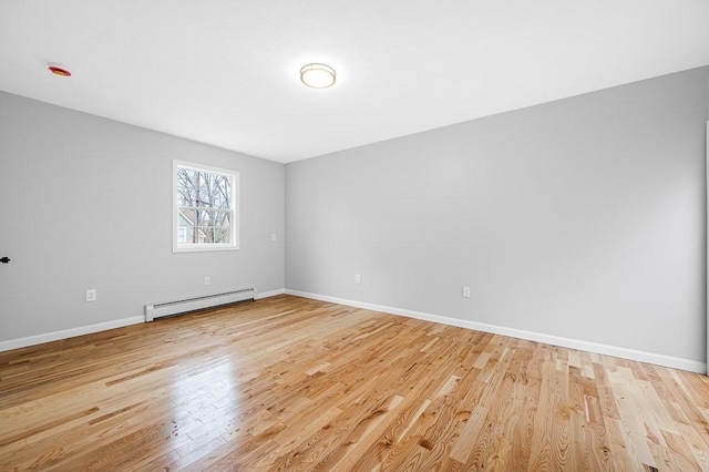 empty room featuring light wood finished floors, a baseboard heating unit, and baseboards