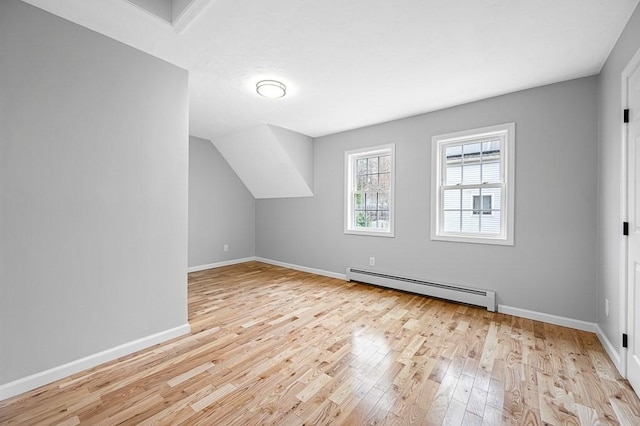 bonus room with baseboard heating, light wood finished floors, and baseboards