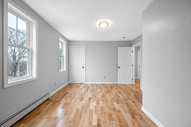 interior space with baseboard heating, baseboards, and light wood-style flooring