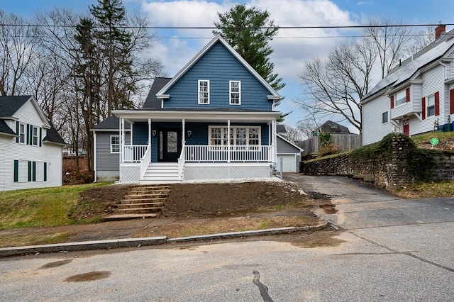 view of front of home with an outbuilding, a detached garage, covered porch, and stairs