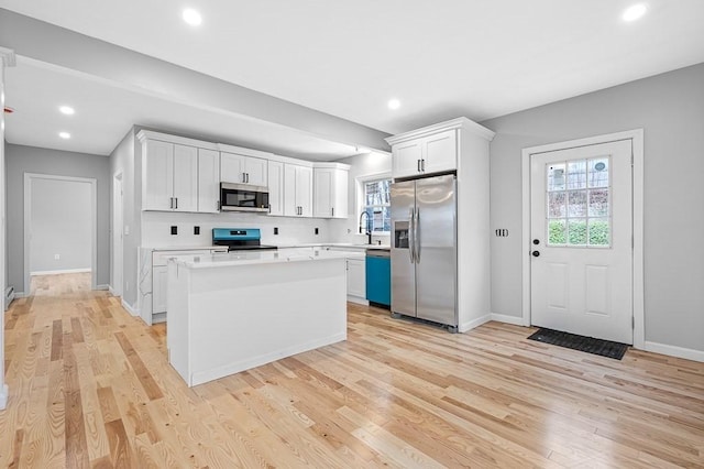 kitchen with light countertops, appliances with stainless steel finishes, a sink, and a wealth of natural light
