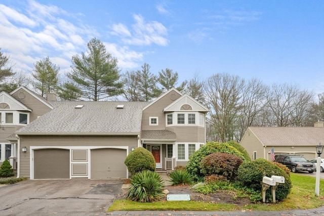 view of front facade featuring driveway, a shingled roof, and an attached garage