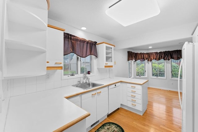 kitchen featuring open shelves, white cabinetry, a sink, white appliances, and a peninsula