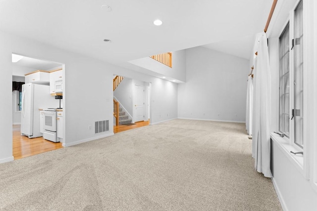 living room with visible vents, light carpet, baseboards, and stairs