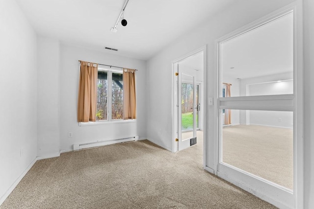 carpeted empty room featuring a baseboard heating unit, visible vents, and track lighting