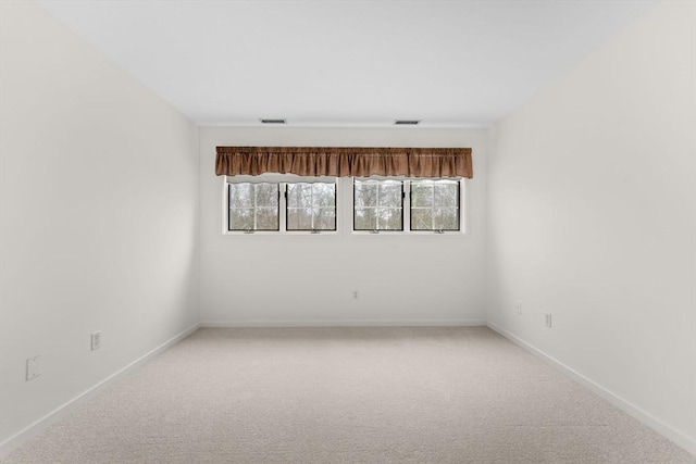 spare room with light carpet, plenty of natural light, visible vents, and baseboards