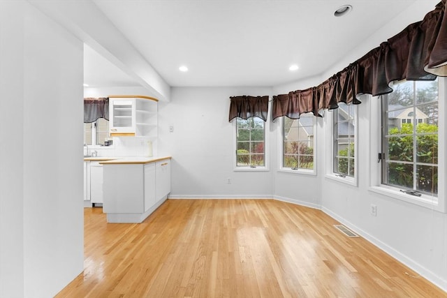 unfurnished dining area featuring light wood-type flooring, visible vents, baseboards, and recessed lighting