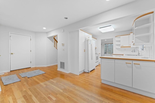 kitchen featuring open shelves, light wood-style floors, white cabinets, a sink, and white appliances