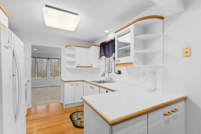 kitchen with a sink, white cabinets, freestanding refrigerator, decorative backsplash, and open shelves