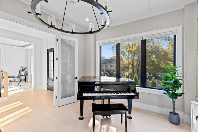 miscellaneous room with french doors, light hardwood / wood-style flooring, an inviting chandelier, and ornamental molding