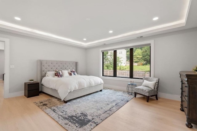 bedroom with a raised ceiling and light hardwood / wood-style flooring