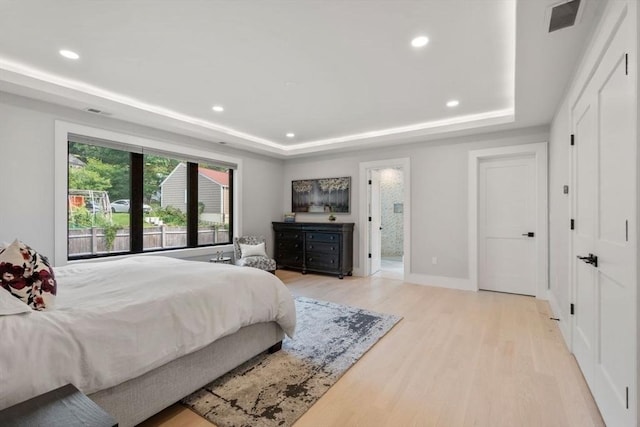 bedroom featuring a raised ceiling and light wood-type flooring