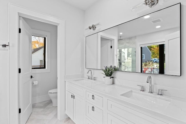 bathroom featuring plenty of natural light, toilet, walk in shower, and vanity