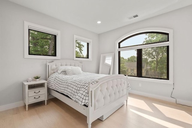 bedroom with multiple windows and light hardwood / wood-style flooring