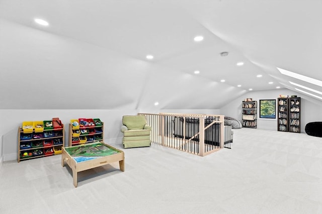 recreation room with vaulted ceiling with skylight and light colored carpet