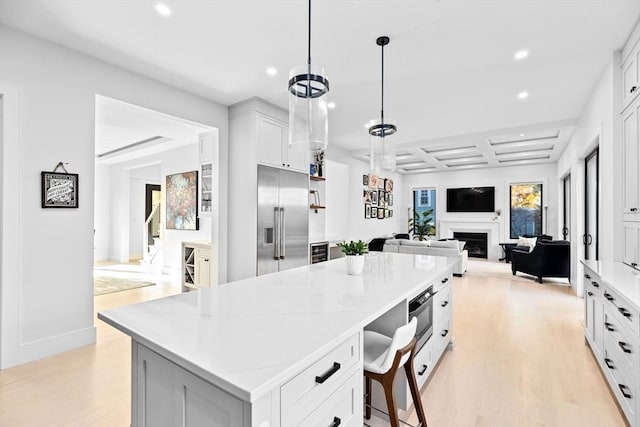 kitchen with coffered ceiling, stainless steel built in refrigerator, pendant lighting, a center island, and white cabinetry