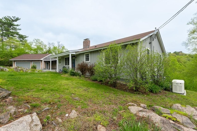 5 Indian Hl, Beverly, MA 01915 - back of property with a chimney, a lawn, board and batten siding, and an attached garage